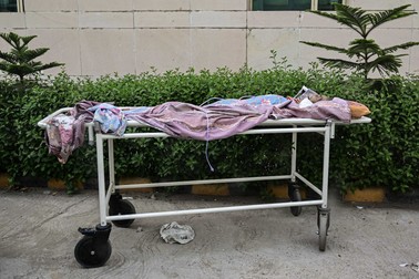 Trupul unui bărbat, pe o targă în fața spitalului, care a murit după ce în spital nu a mai putut fi primit din lipsă de paturi libere. Foto: Hepta