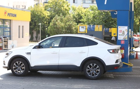 Imaginea prezintă un autoturism SUV coupe alb oprit la pompa unei stații de carburanți Petrom.
