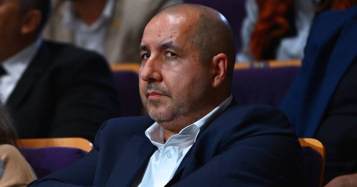 Vasile Sile Pușcaș, in sacou inchis la culoare si camasa alba, cu mainile impreunate la piept, în timpul dezbaterii prezidențiale dintre Nicușor Dan și George Simion, înainte de cel de-al doilea tur al alegerilor prezidențiale, Euronews, București, România, joi, 8 mai 2025.