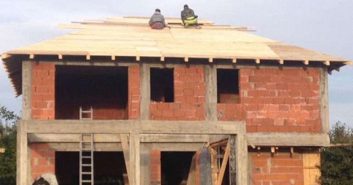 Casă de cărămidă din Galați în construcție. Pe acoperiș, muncitorii lucrează de zor