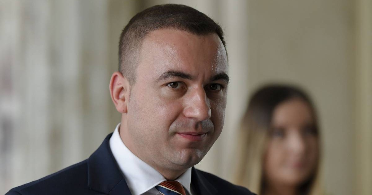 În imagine Bogdan Ivan, îmbrăcat la costum, privește spre aparatul foto
