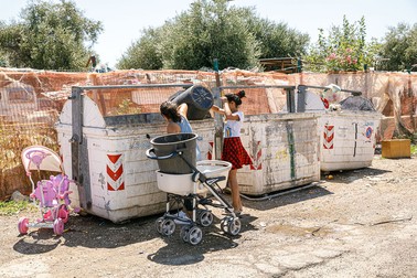 Două fete din tabără aruncă gunoiul menajer în containerul de lângă tabără