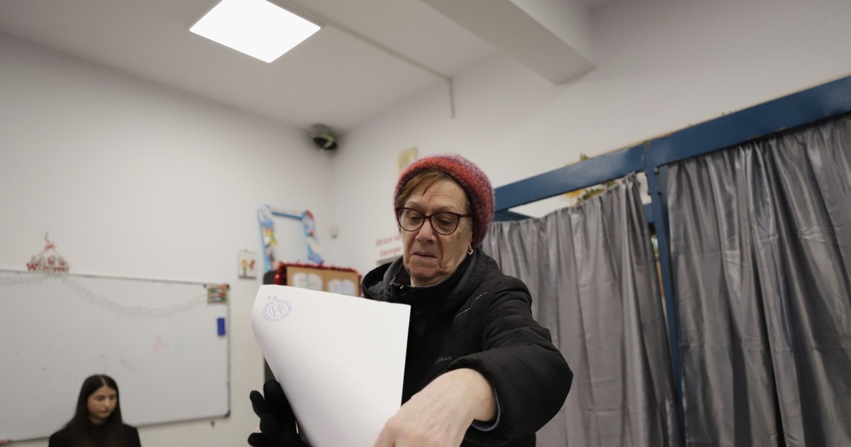 o femeie care introduce un buletin de vot în urnă