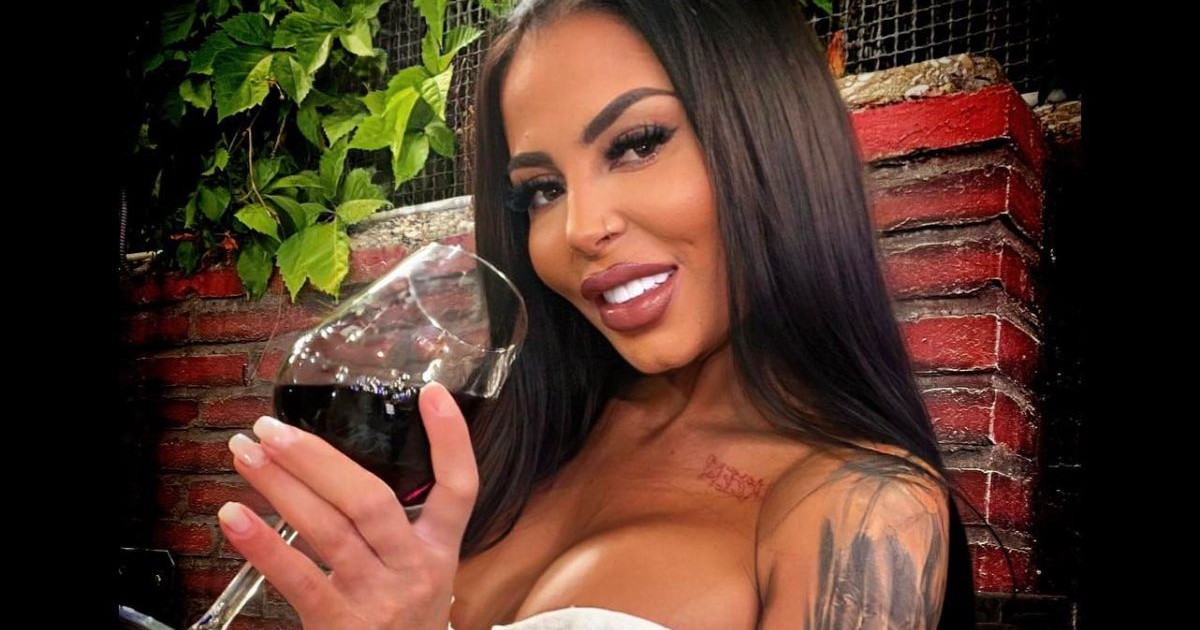 Denisa Maria Adas, românca dispărută în Italia, îmbrăcată cu un top alb, în timp ce ține în mână un pahar de vin roșu