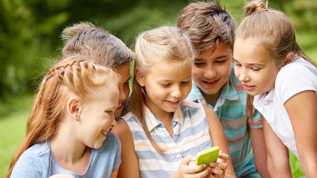 Mai mulți copii se uită la un telefon cu carcasă verde
