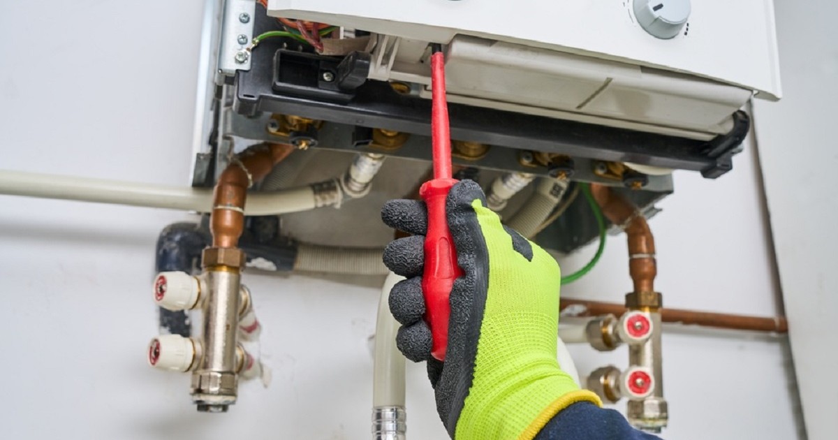 De ce curge apă din centrala termică - Un instalator repara o centrală termică Foto: Shutterstock.com