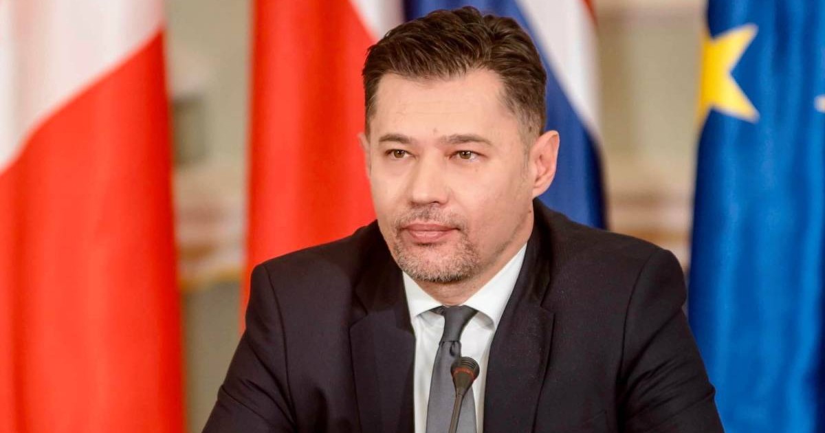 Olexander Scherba, Ambasadorul ucrainean în Africa de Sud, in costum negru, camasa alba, intr-un context oficial cu steaguri in spate