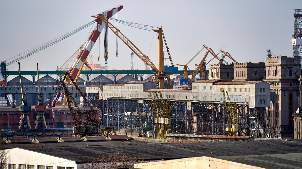 Imagine din Portul Constanța, acolo unde se vedem cum macaralele încarcă mai multe containere pe o navă cargo