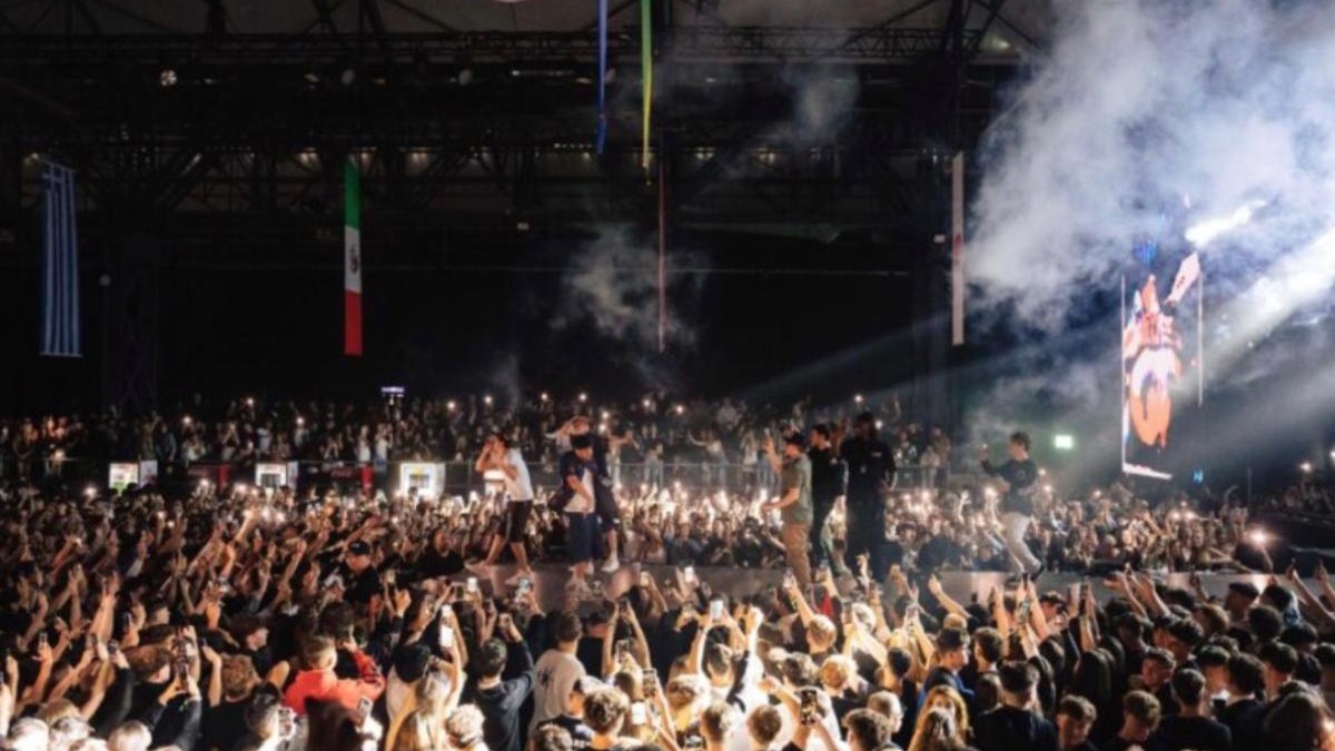 O mulțime de oameni, în jurul unei scene pe care are loc un concert.