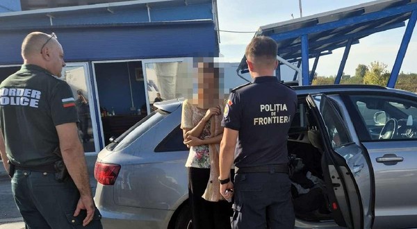 Doi polițiști de frontieră, unul din Bulgaria si unul din România, discută  cu o femeie langa o masina gri, la vama Calafat