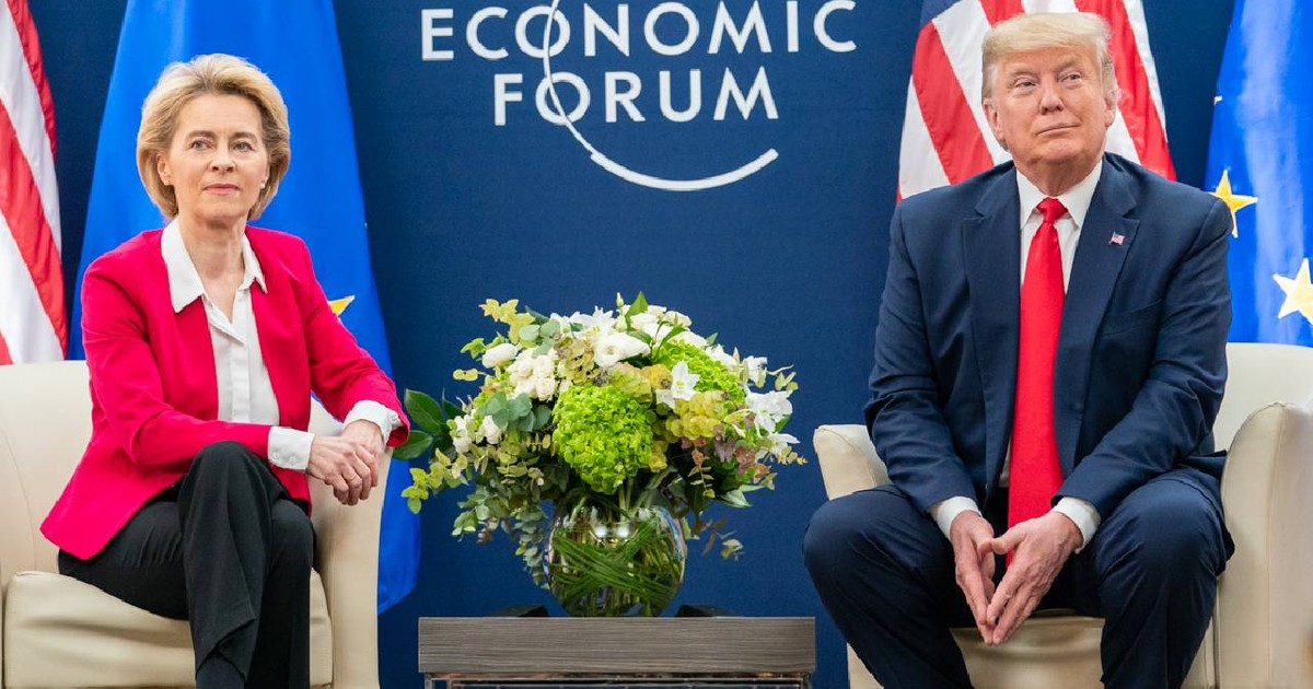 Ursula vonder leyen (stânga) și Donald Trump (dreapta) la un eveniment economic, între ei stă o vază cu flori și amândoi privesc obiectivul foto spre care zâmbesc