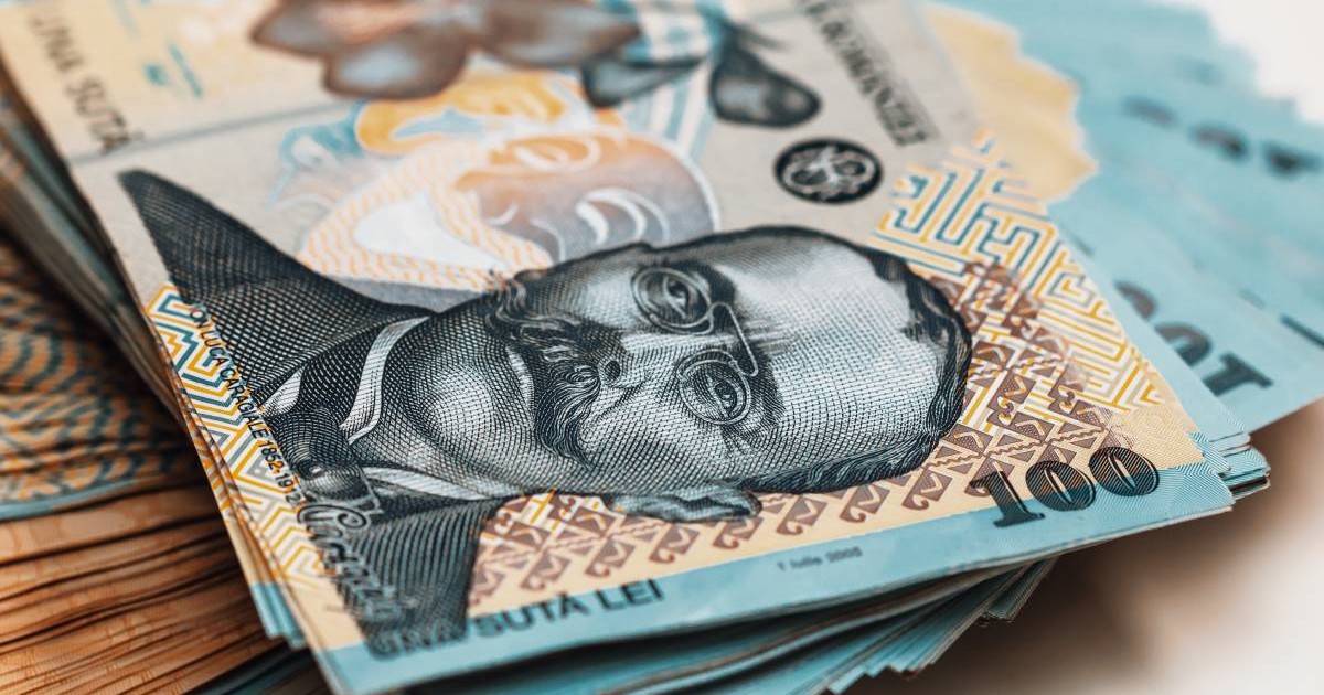 Zeci de hârtii de 100 de lei întinse pe o masă