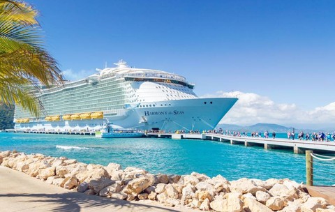 Un vas de croazieră ancorat în port, iar turiștii coboară pentru a vizita insula