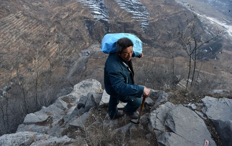 FOTO| La 60 de ani, un poștaș din China se cațără zilnic pe drumuri de munte pentru a livra ziare și scrisori