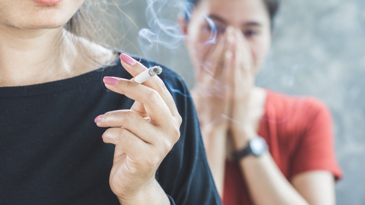 Cum scapi de mirosul de tutun din locuința ta Ă Imagine cu o femeie care fumează în prezenţa alteia, sugerând fumatul pasiv