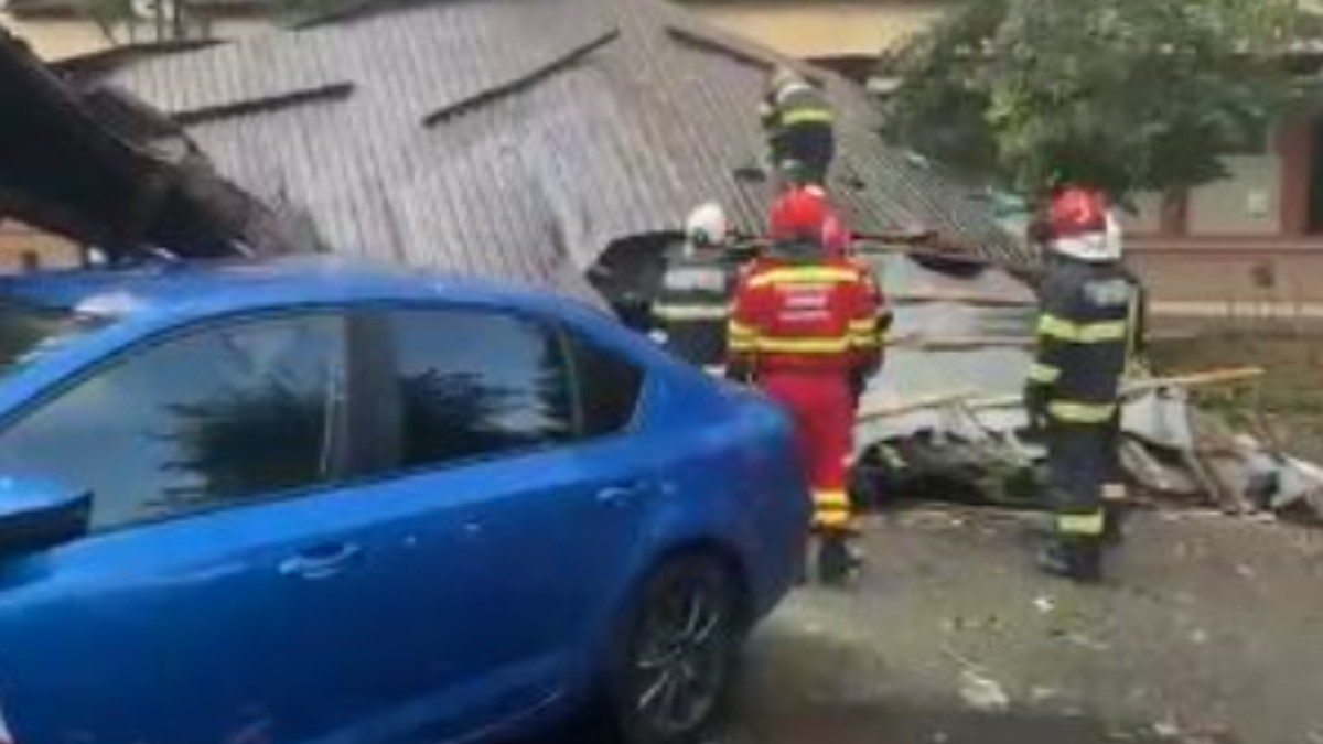 În imagine se observă intervenția pompierilor după ce o parte din acoperișul unei clădiri s-a prăbușit în urma furtunii. Salvatorii evaluează pagubele și acționează pentru îndepărtarea elementelor desprinse, în timp ce zona este securizată pentru a preveni alte incidente.