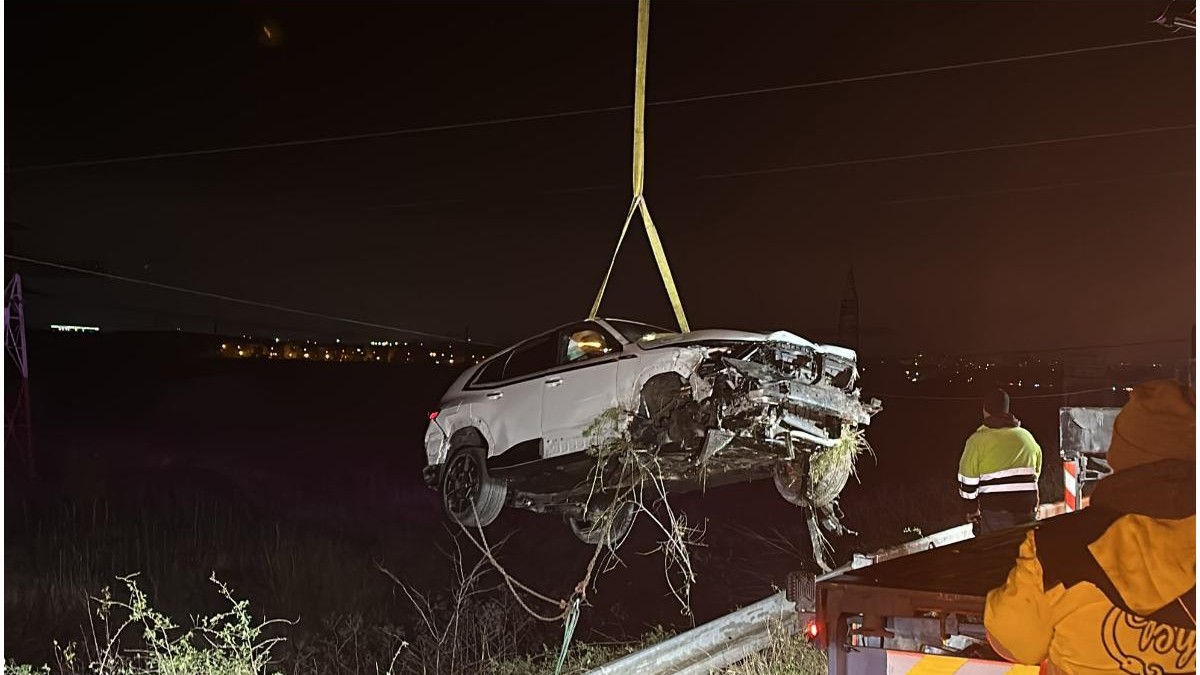 o mașină albă, care s-a răsturnat, ridicată cu chingi pentru a fi așezată pe o platformă