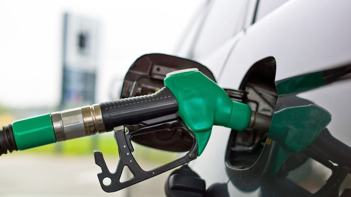O pompă verde alimentează un automobil de culoare neagră.