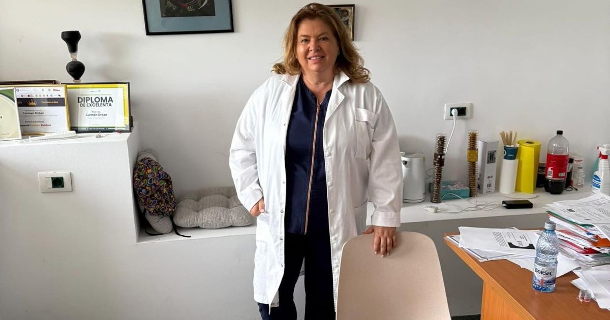 Senatoarea PSD, Carmen Orban, care a refuzat să fie ministrul Sănătății, este îmbrăcată într-un halat alb de doctor, este în cabinetul medical, ține o mână pe scaun, în stânga se văd câteva diplome primite de ea, niște tablouri în spate, o rolă de hârtie și o sticlă de suc, iar în dreapta este colțul unui birou cu hârtii pe el și o sticlă mică de apă minerală