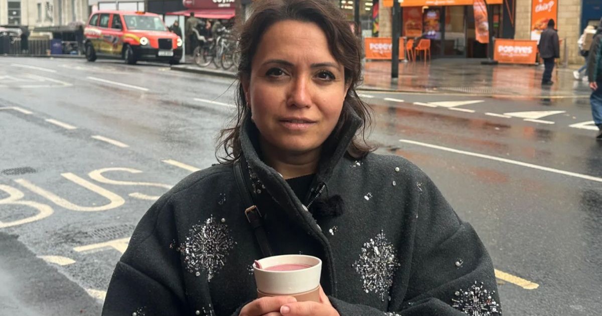 O femeie cu o cafea în mână, aflată pe stradă într-o zi ploioasă, în Londra, octombrie 2025