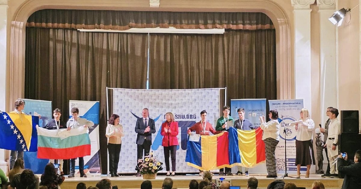 Mai mulți elevi și profesori pe o scenă, în Bulgaria, țin în mână steagurile României și Bulgariei