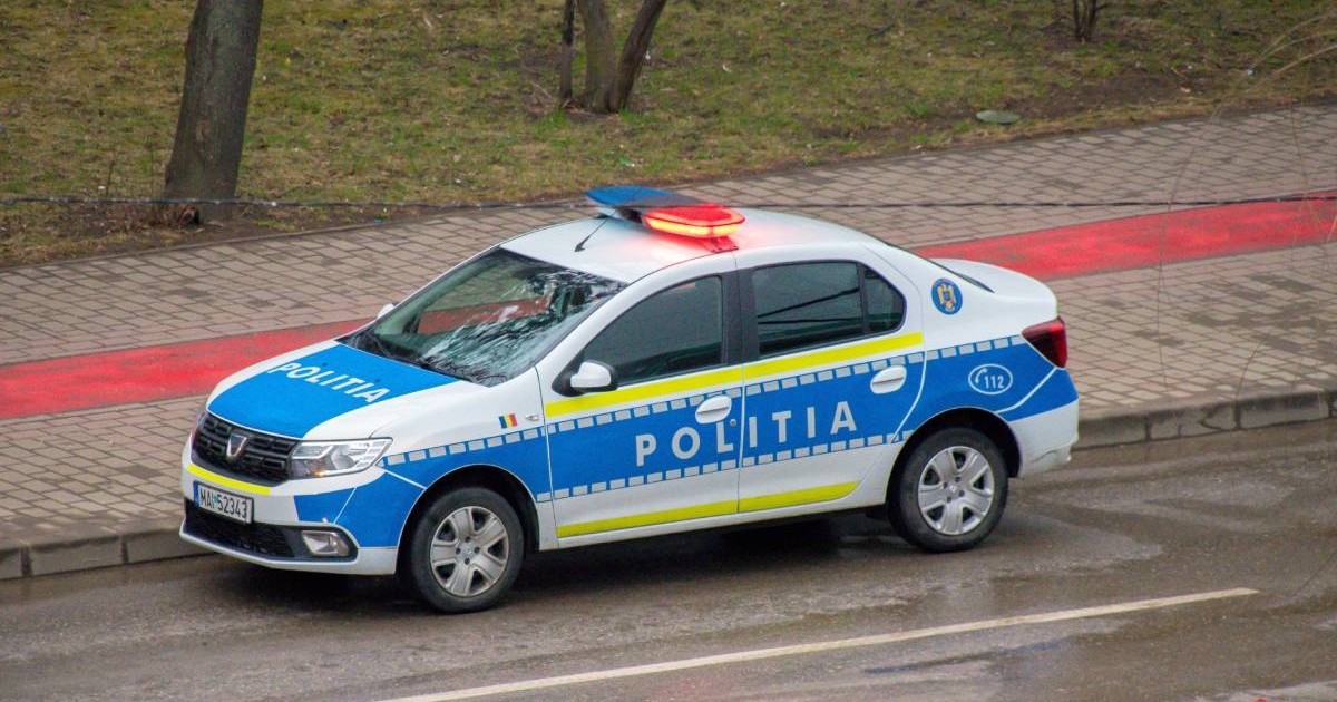 O mașină de Poliție, în timpul unei intervenții la fața locului, are girofarurile pornite și se deplasează pe stradă