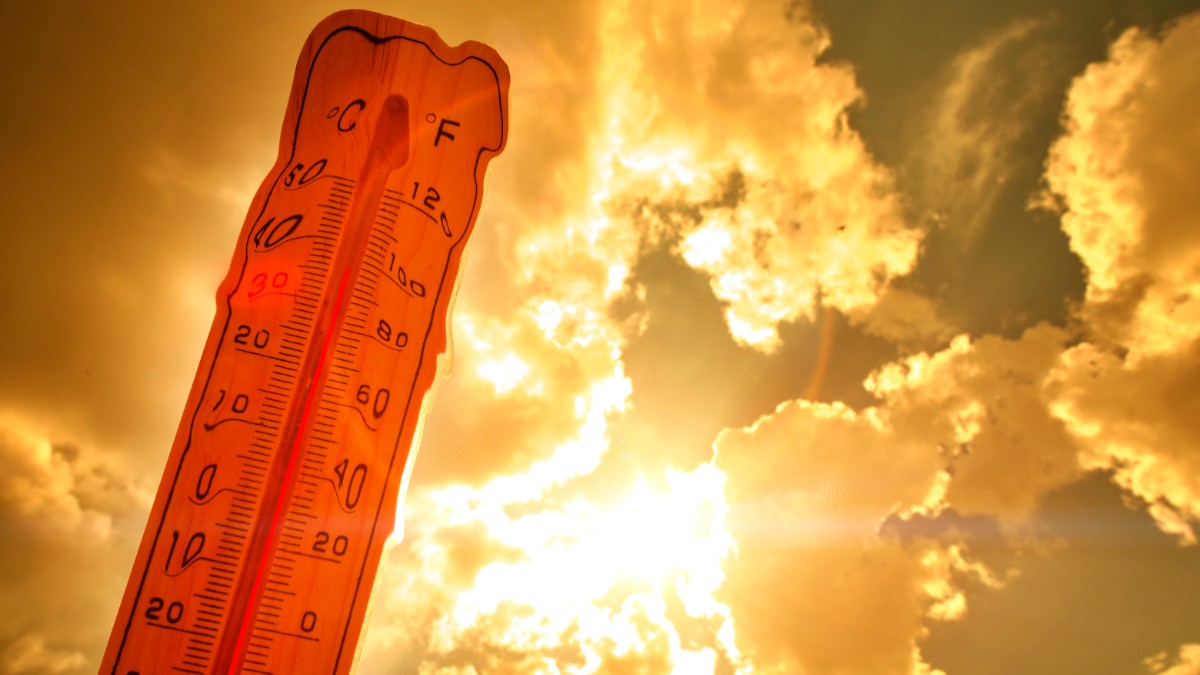 Un termometru de lemn este profilat pe fundalul unui cer luminos și însorit, indicând o temperatură ridicată într-o zi caniculară.