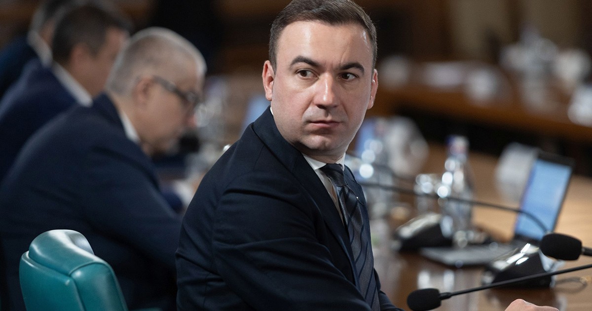 Bogdan Ivan, ministrul Investițiilor și Proiectelor Europene, participă la o ședință de guvern, este întors la masă și privește în spate