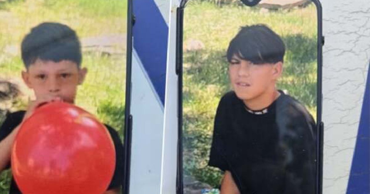 Doi copii, unul mai mic suflă într-un balon roșu, iar cel mai mare se află în natură