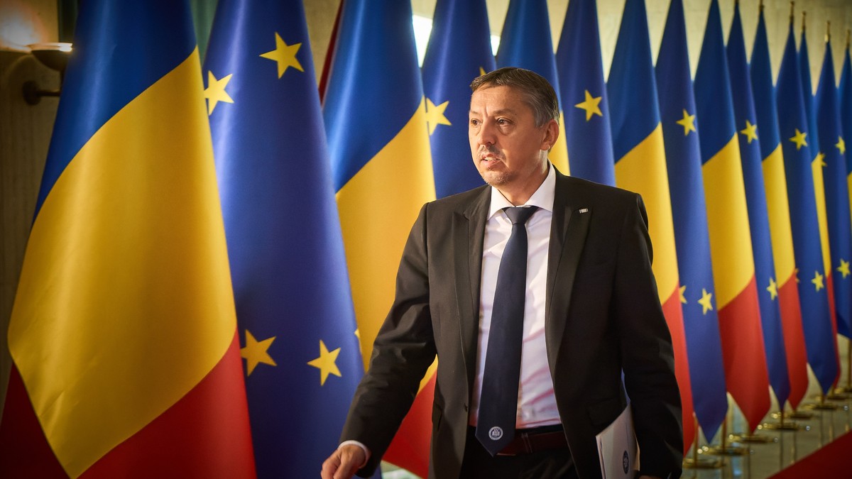 Ministrul Educației, Daniel David, alături de mai multe steaguri ale României și UE.