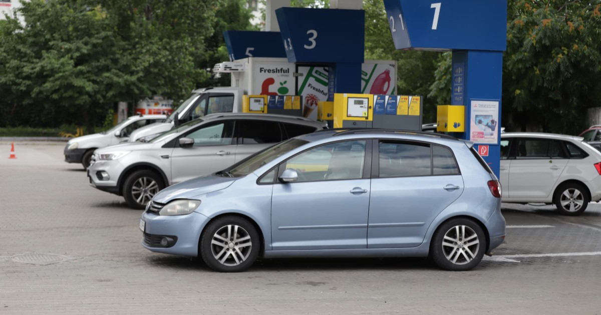 Mai multe mașini sunt oprite pentru alimentat la pompele unei benzinării având în prim-plan un autoturism Volkswagen Golf Plus albastru-deschis.