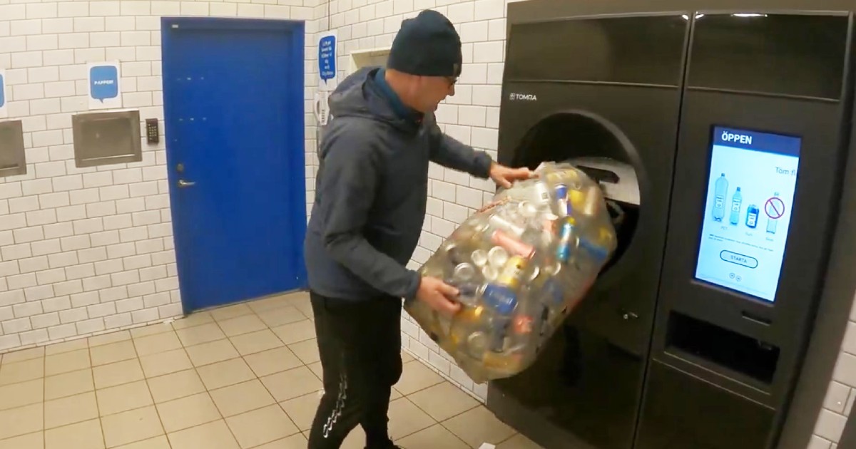Imaginea surprinde un bărbat care golește un sac mare plin cu doze de aluminiu într-un automat industrial de colectare și reciclare a ambalajelor, într-un spațiu special amenajat.