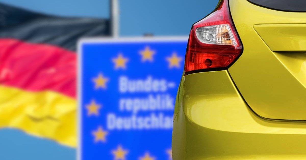 fotografie cu o masina galbena langa steagul germaniei