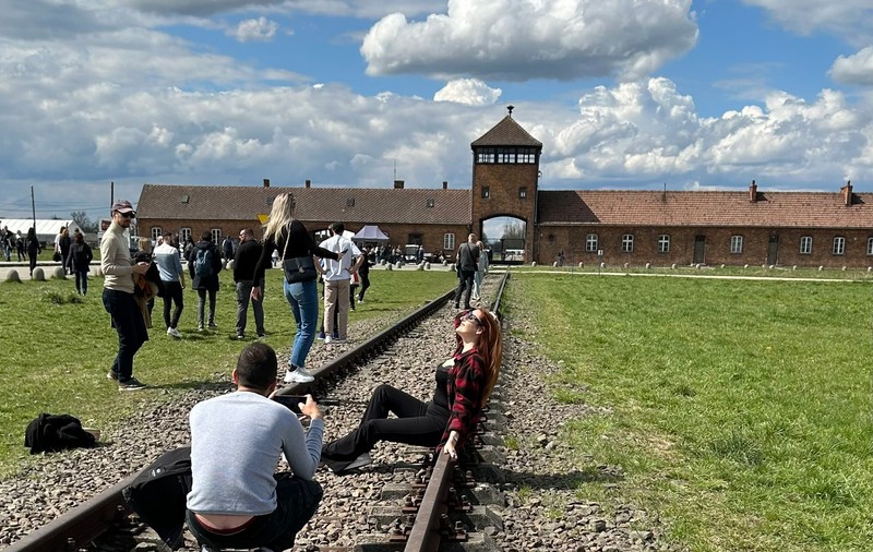 O tânără care pozează lasciv pe șinele de tren de la Auschwitz a stârnit indignare pe internet. „Nu întinați memoria lor”