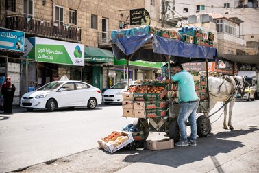 În orașul Dura, un comerciant ambulant vinde legume și fructe proaspete dintr-un atelaj cu cal