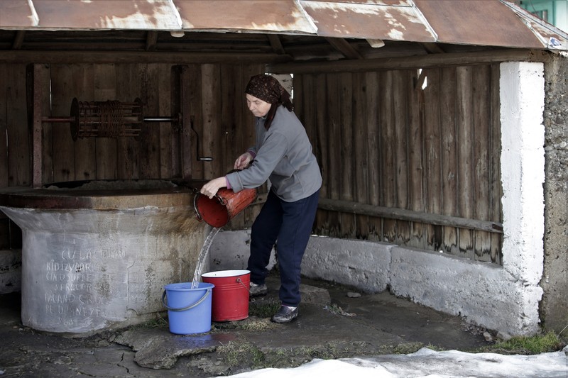 Agafia aduce apă ca să spele rufele, în curte