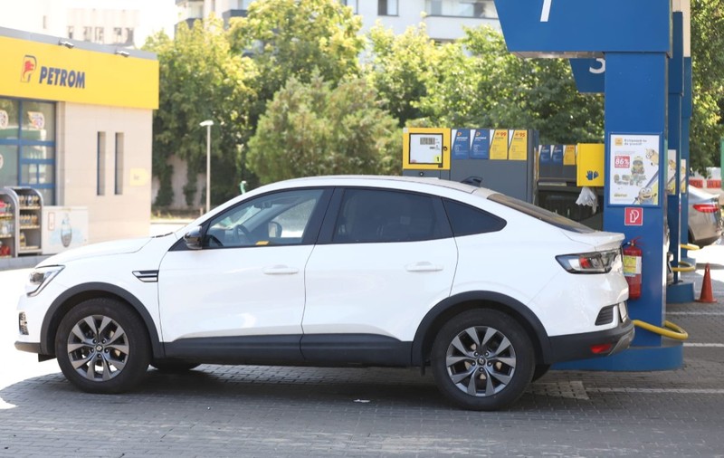 Imaginea prezintă un autoturism SUV coupe alb oprit la pompa unei stații de carburanți Petrom.