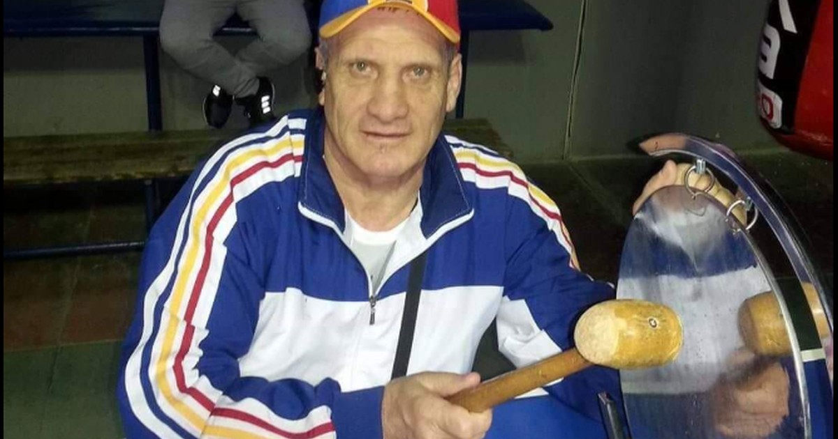 Titi Tudor Prosop, îmbrăcat în trening și cu o șapcă tricoloră pe cap stă pe un scaun și bate gongul într-o sală de box din Ploiești, aprile 2020