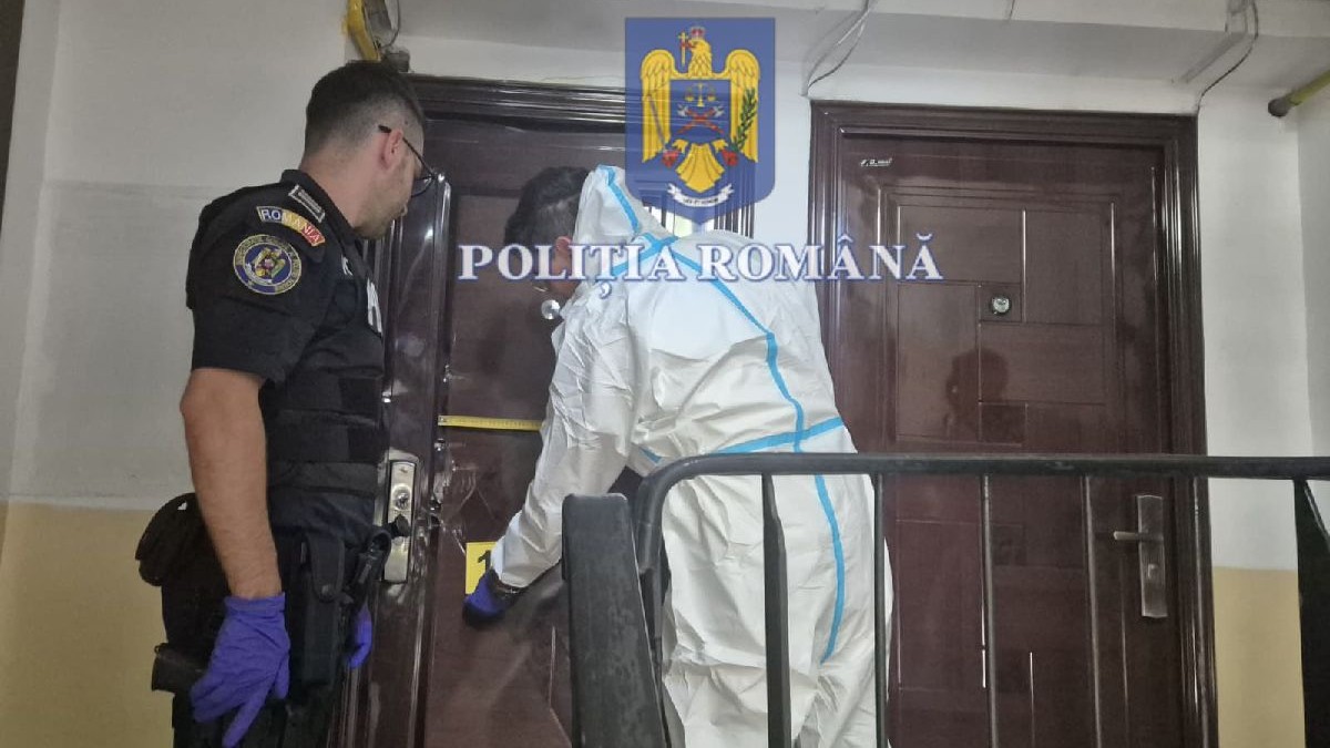Un criminalist și un polițist în timp ce blochează accesul spre locul crimei