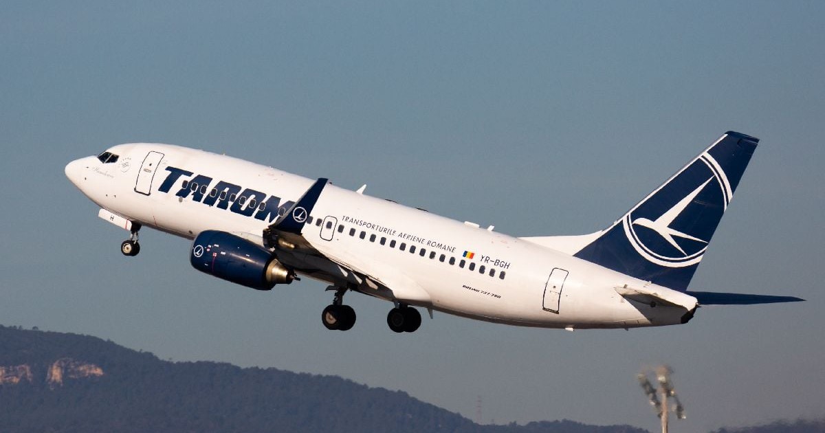 O fotografie a unui avion al companiei TAROM zburând.