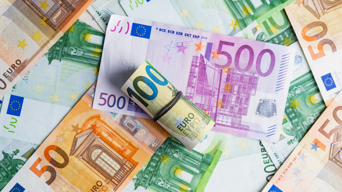 Imaginea prezintă mai multe bancnote euro de diferite valori – 50, 100 și 500 – aranjate pe o suprafață, cu un rulou de bancnote de 100 de euro plasat central. Fotografia evidențiază diversitatea bancnotelor și simbolizează conceptul de bani, economie sau tranzacții financiare.