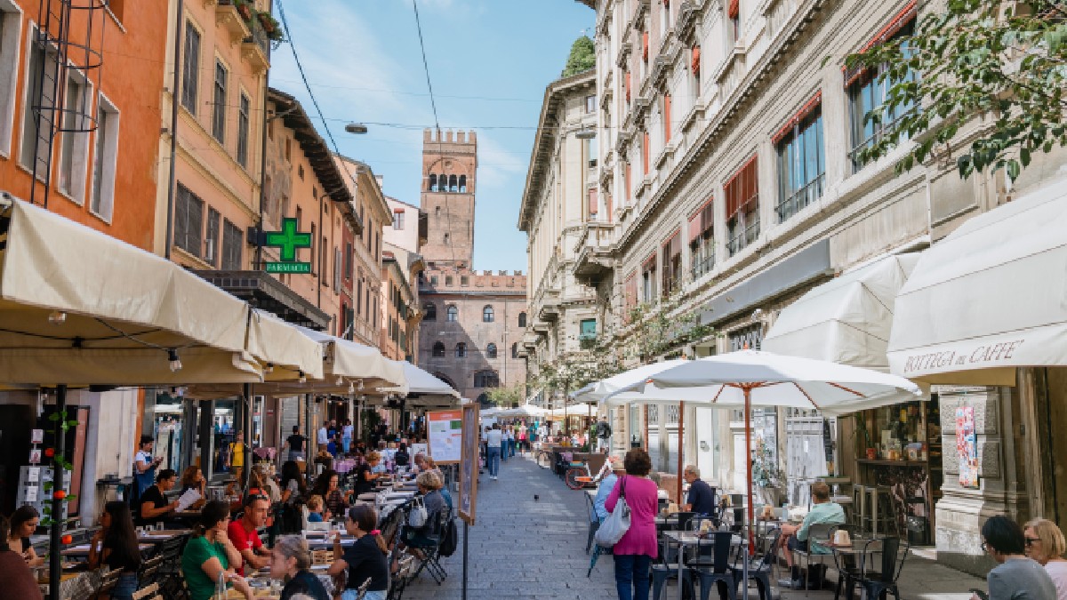Oamenii iau prânzul pe strada Pescherie Vecchie, lângă faimoasa piață alimentară italiană din centrul vechi al orașului Bologna.