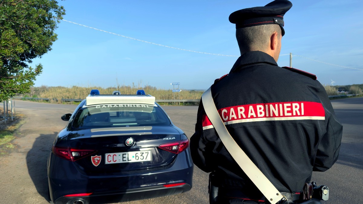 Un politist italian pe o autotradă, lângă o mașină de carabinieri, în timp ce controlează traficul