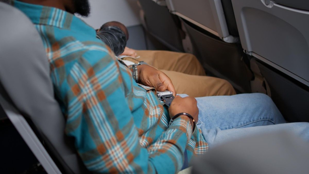 bărbat care își pune centura de siguranța în avion