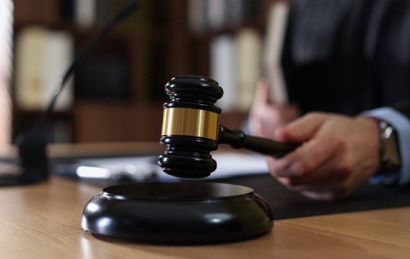 Judecător izbește cu un ciocănel în masa de lemn, într-o sală de judecată 