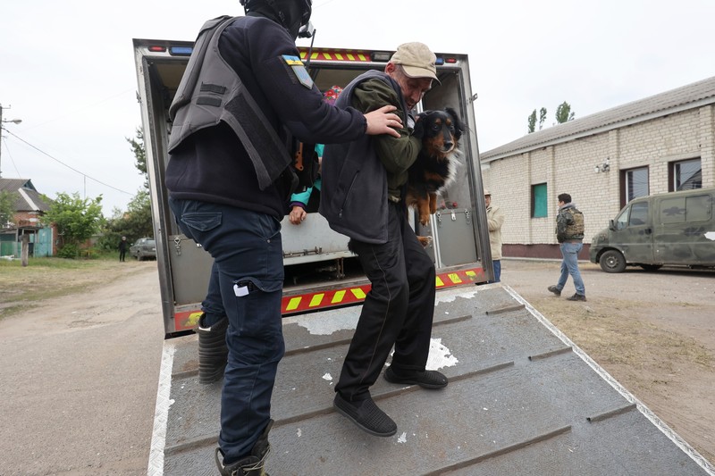 KHARKIV REGION, UKRAINE - MAY 17, 2024 - A police officer helps an elderly man carrying a dog go down a ramp during the evacuation from Vovchansk which is under constant Russian shelling, Kharkiv region, northeastern Ukraine.,Image: 873949416, License: Rights-managed, Restrictions: This photo cannot be distributed in the Russian Federation., Model Release: no