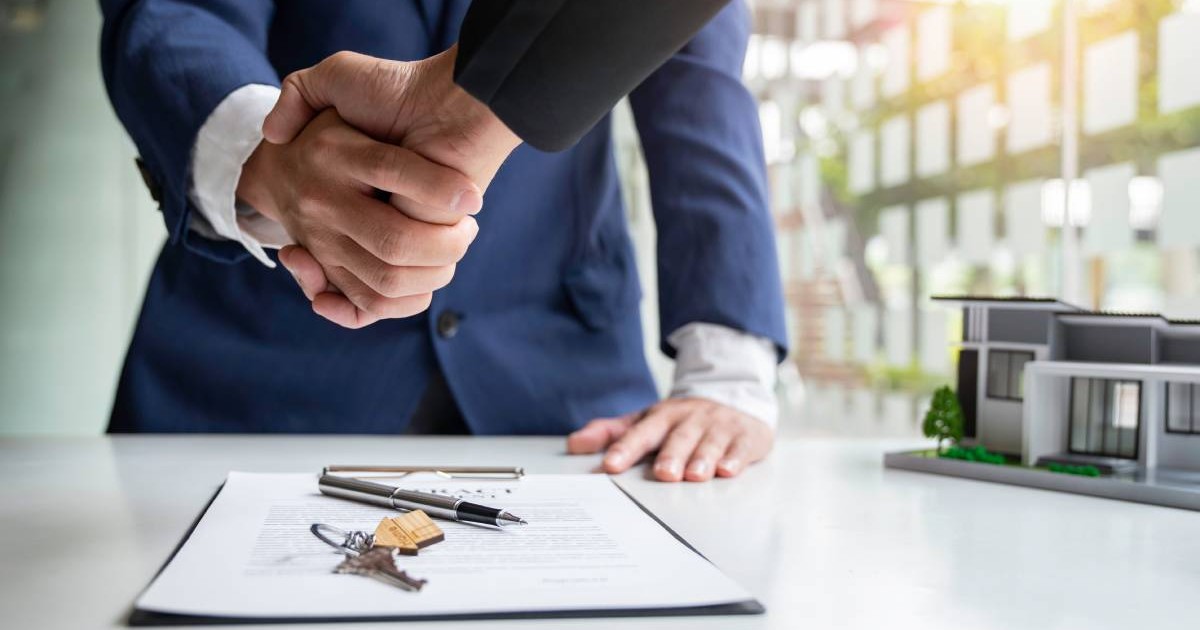 Doi bărbați în timp ce dau mân pentru că au semnat un contract de vânzare - cumpărare pentru o proprietate imobiliară