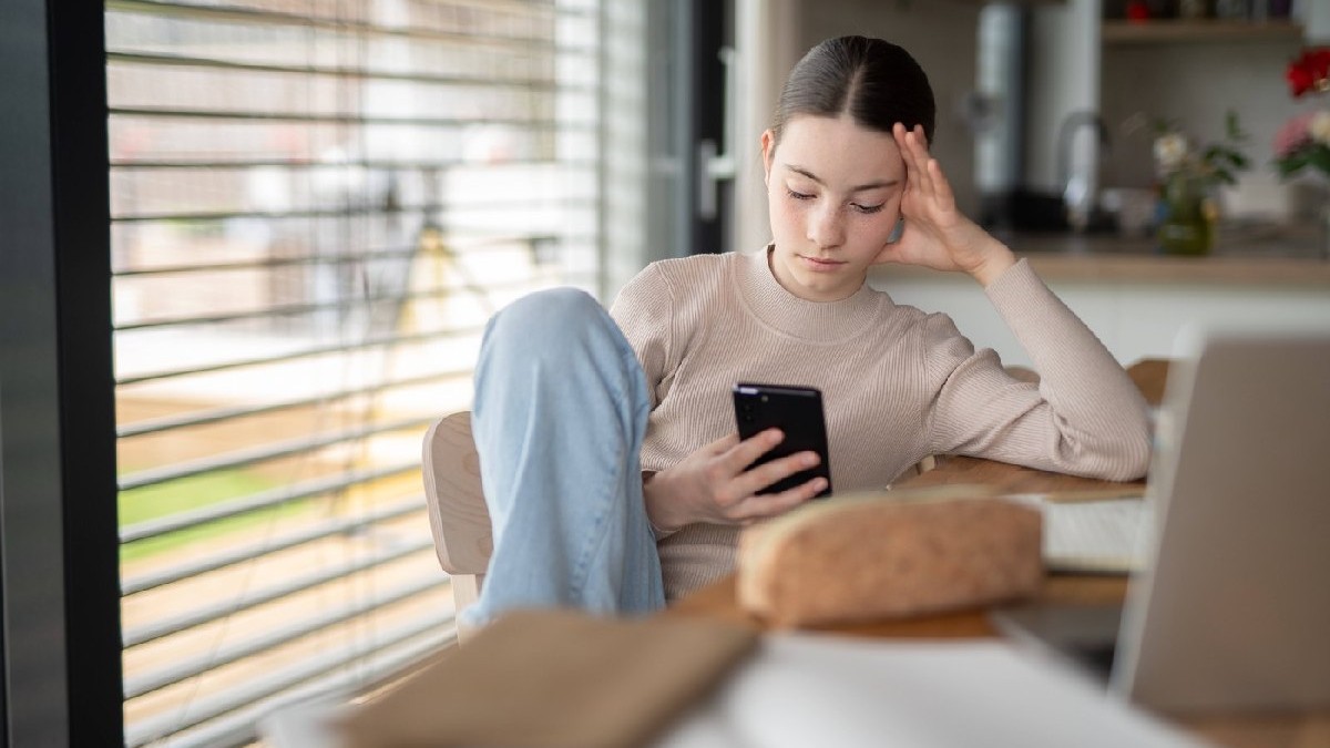 Adolescentă stresată verificându-și telefonul, derulând paginile de social media.