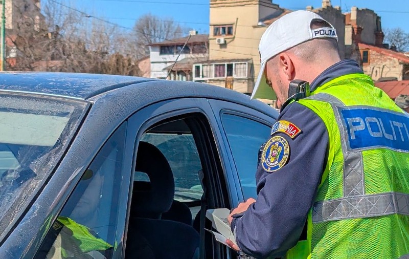 Un polițist verifică actele unui șofer dintr-o mașină neagră
