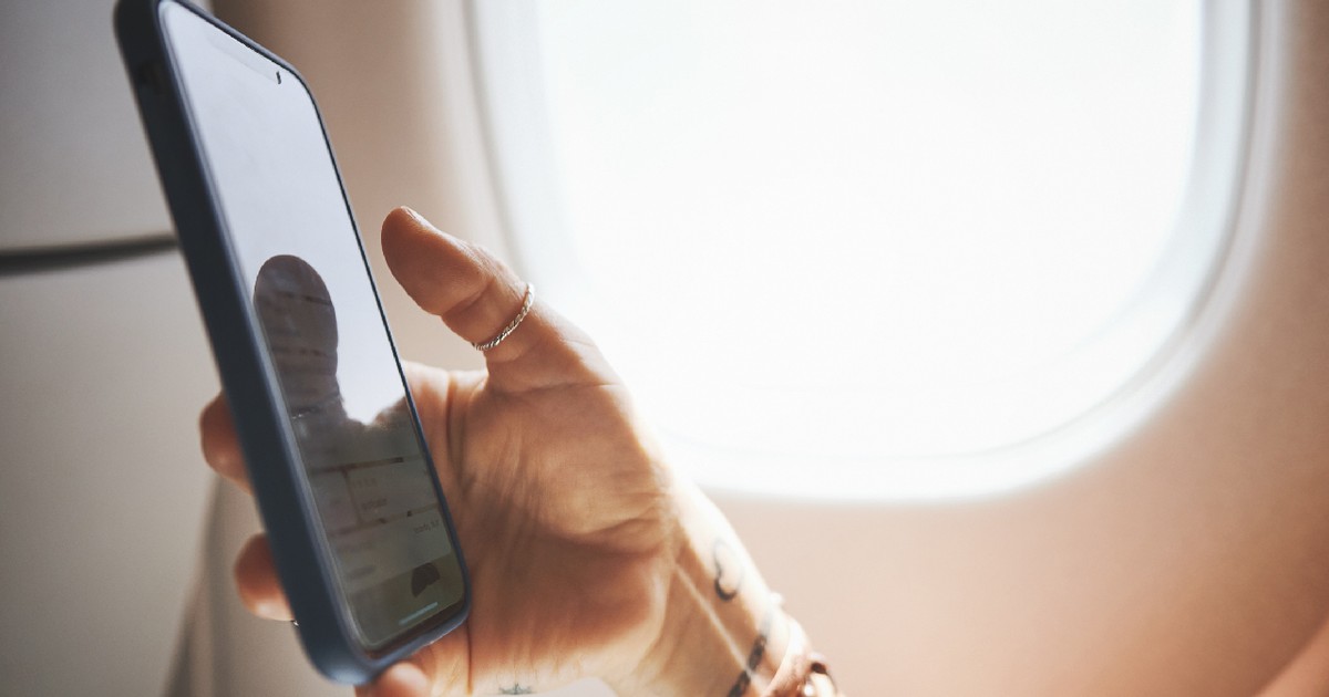 O femeie ține un telefon in mana in timpul unui zbor